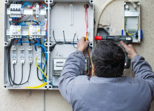 Electrician installing wiring in a residential setting, showcasing the quality and safety measures of JH Midland Builder.